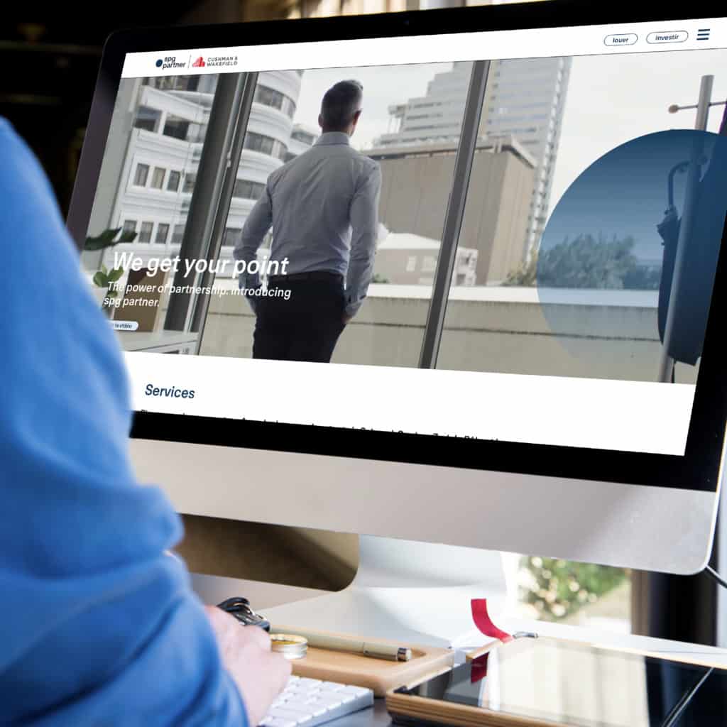 Une personne utilise un ordinateur de bureau pour consulter un site web représentant un homme d'affaires regardant par la fenêtre les bâtiments de la ville, avec la phrase